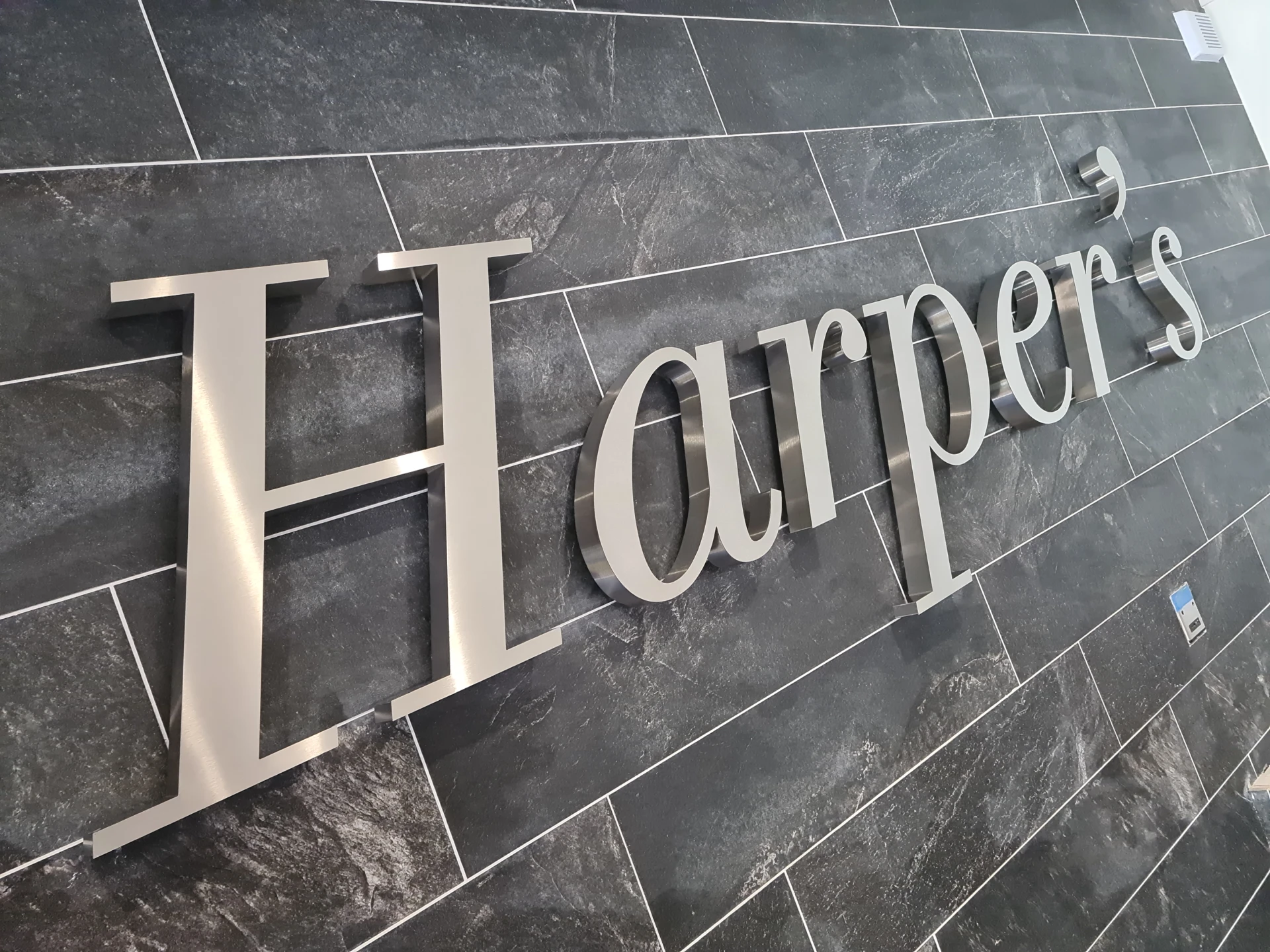Harpers metal lettering on a dark tiled wall.