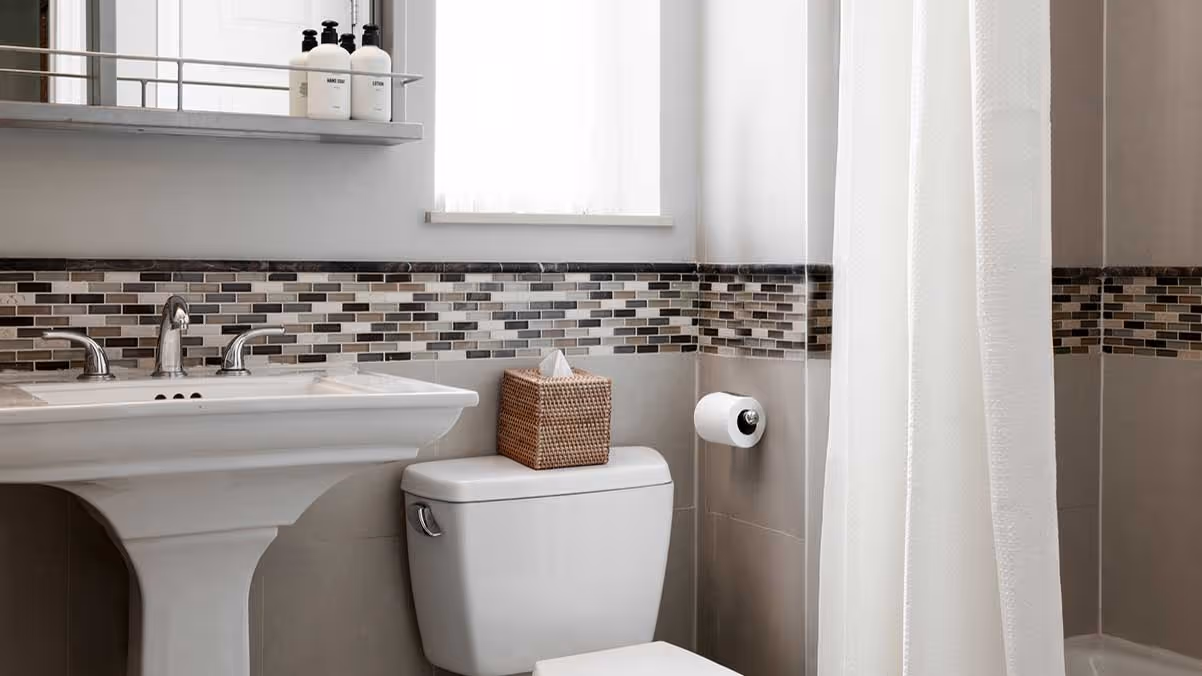 Clean bathroom with white pedestal sink, toilet with tissue box on top, and bathtub with white shower curtain.