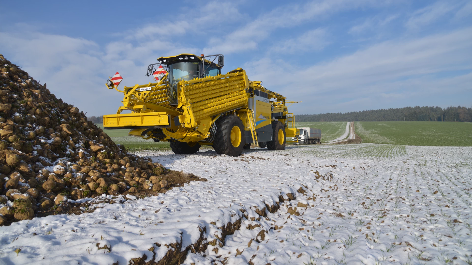 A ROPA Maus 6 in road transport position in a field with a sugar beet pile and snow on the ground.