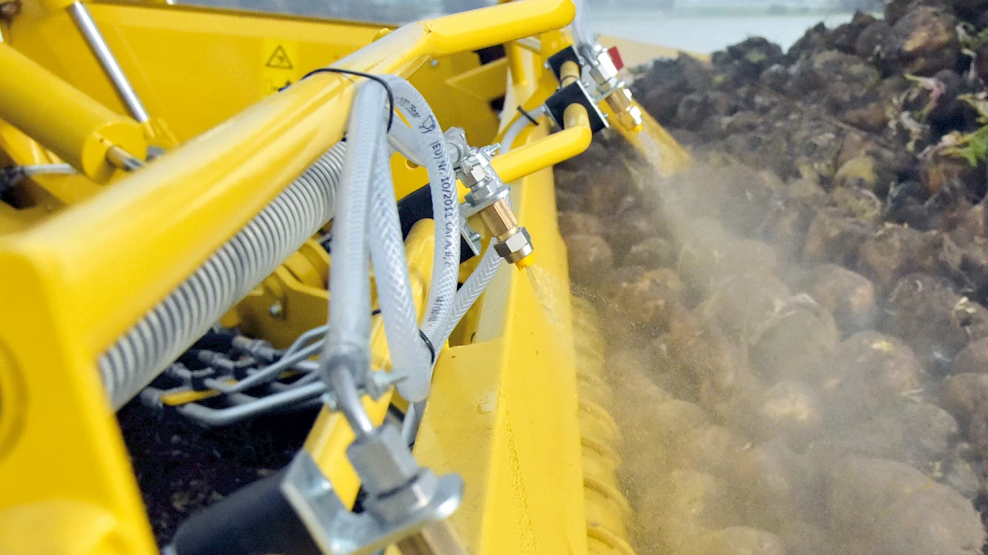 The water spray system nozzles on the pickup of the ROPA Maus 6 spraying water on the incoming beets