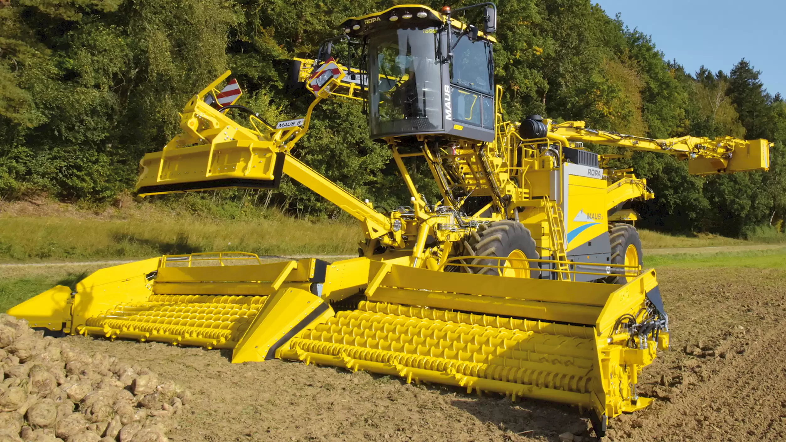 A ROPA Maus 6 fully unfolded in a field in front of a field pile of sugar beets.