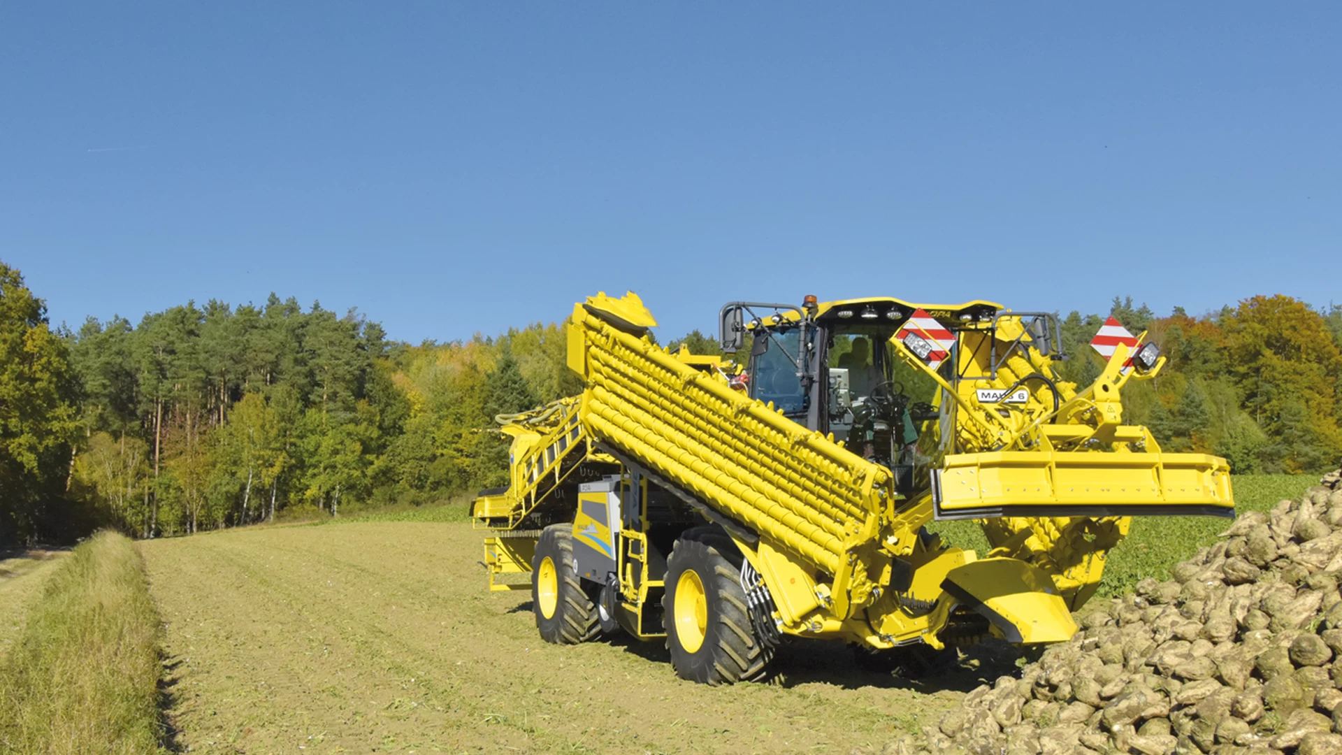 The ROPA Maus 6 partially unfolded in front of a field pile of sugar beets. Step 2/7 of the automated unfolding process.