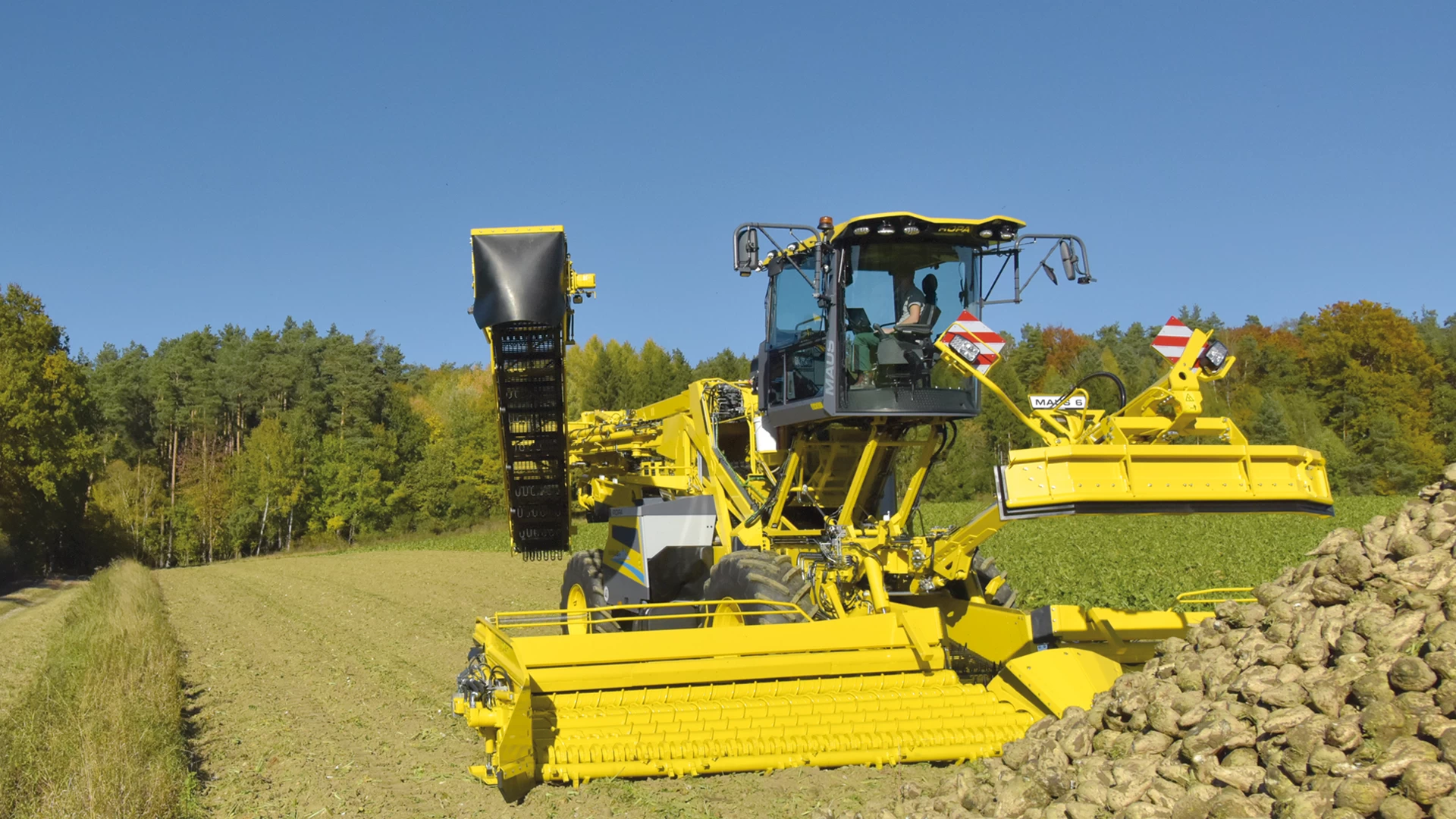 The ROPA Maus 6 partially unfolded in front of a field pile of sugar beets. Step 5/7 of the automated unfolding process.