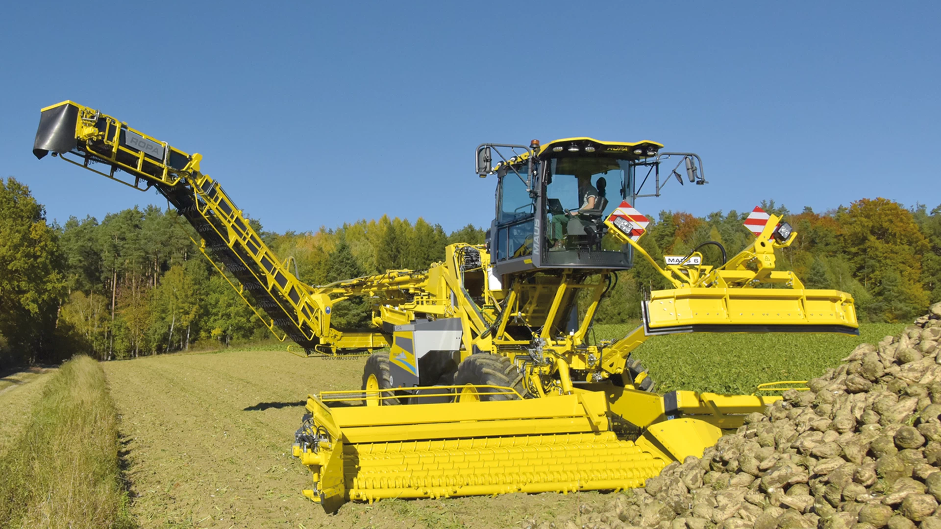 The ROPA Maus 6 partially unfolded in front of a field pile of sugar beets. Step 6/7 of the automated unfolding process.