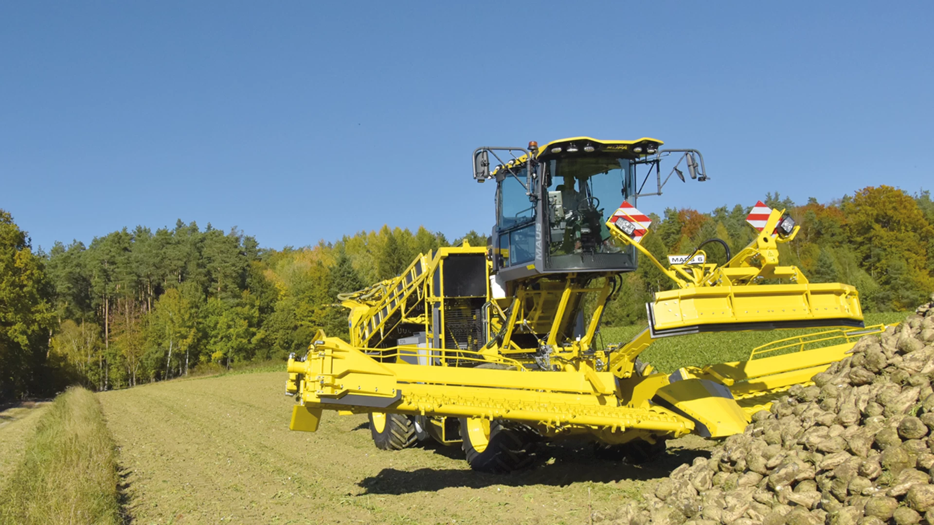 The ROPA Maus 6 partially unfolded in front of a field pile of sugar beets. Step 3/7 of the automated unfolding process.