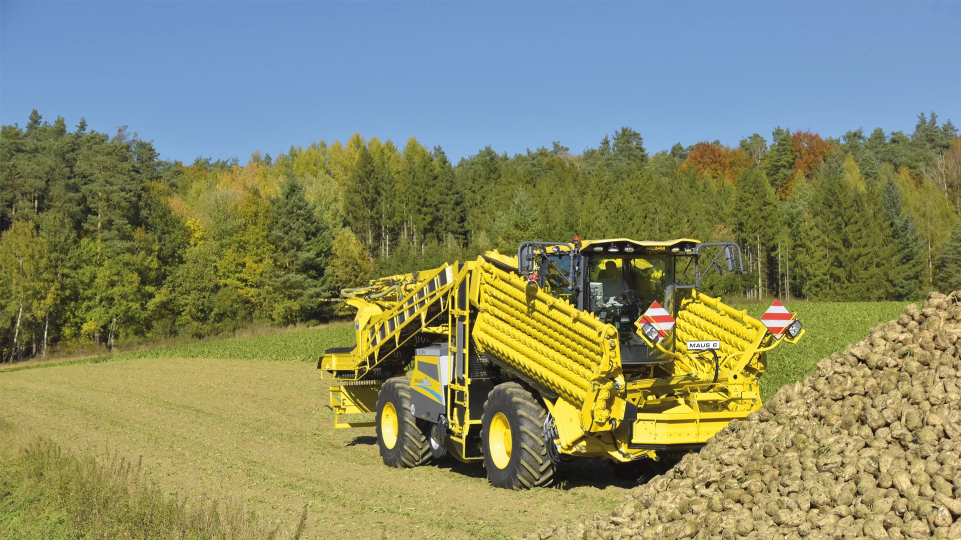 The ROPA Maus 6 fully folded in road-transport in front a field pile of sugar beets. Step 1/7 of the automated unfolding process.