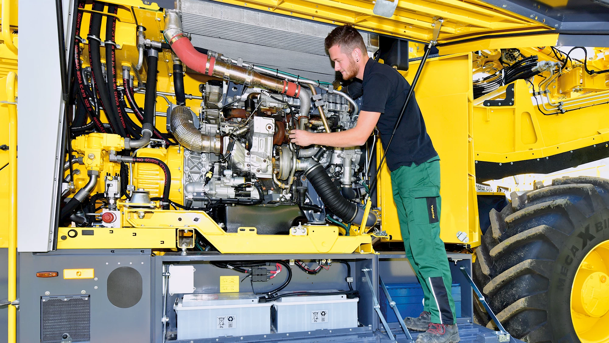 An operator viewing the Mercedes Benz motor on a Maus 6 from the side engine compartment door