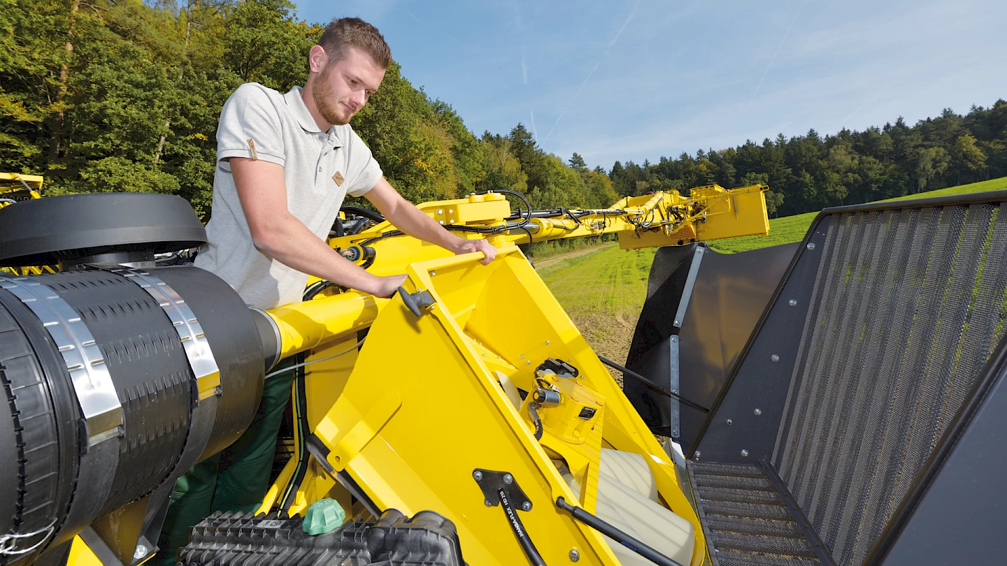 An operator opening up the top engine access doors on the Maus 6