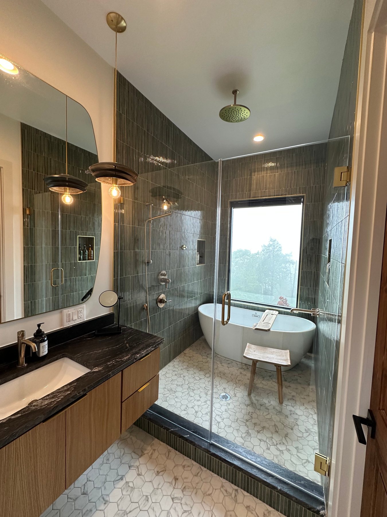 Primary bathroom in dark tile with a freestanding tub