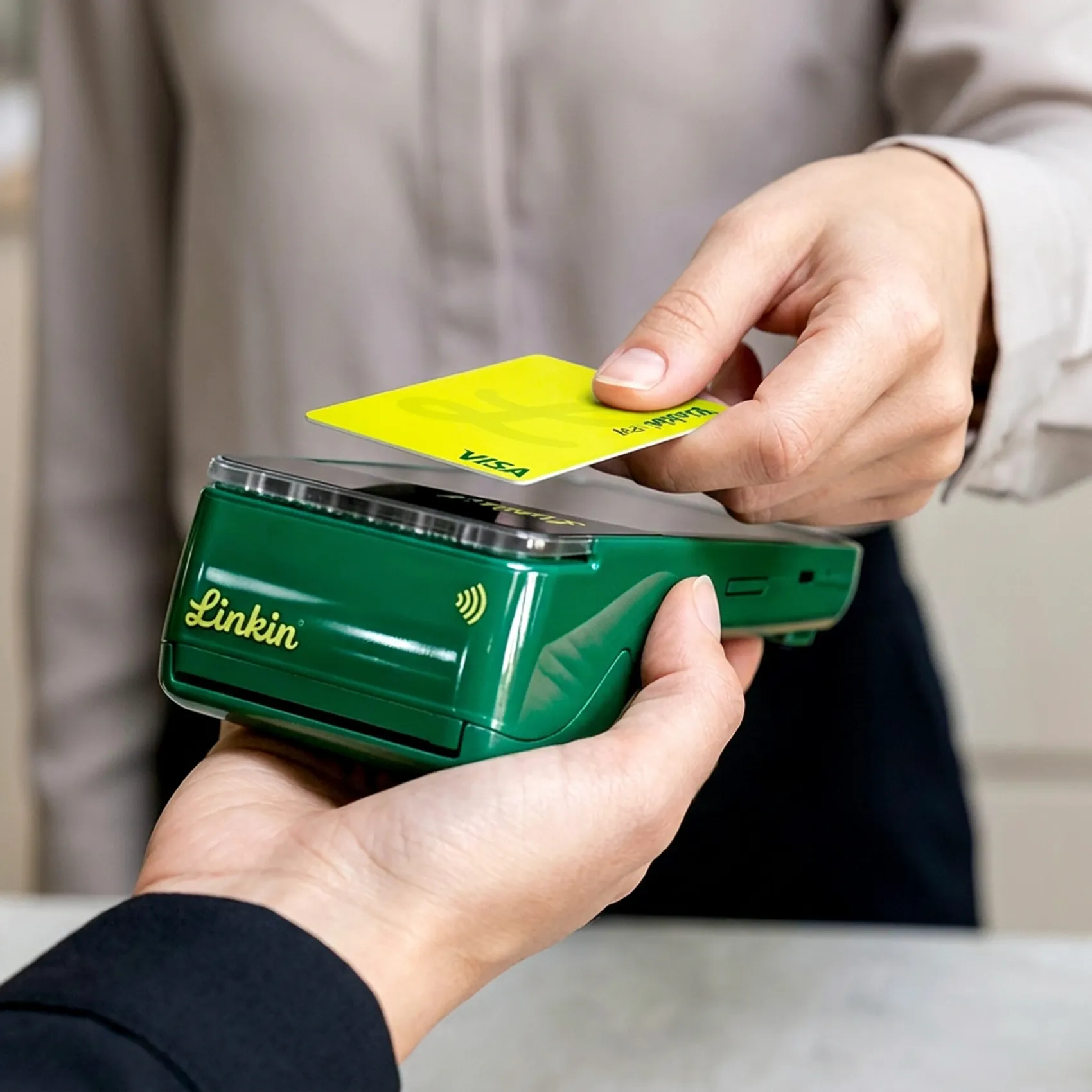 Persona pagando con tarjeta acercándola al POS Linkin
