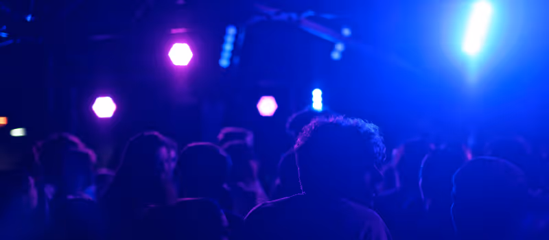 Fullt dansgolv med folk som dansar till en DJ med blå partybelysning