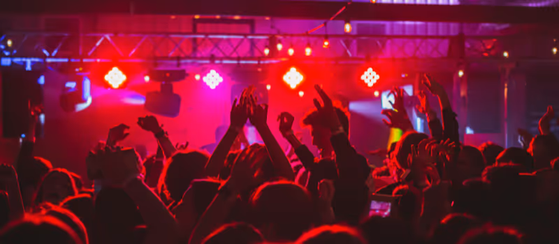 Publik som dansar på ett dansgolv med DJ och festlig partybelysning