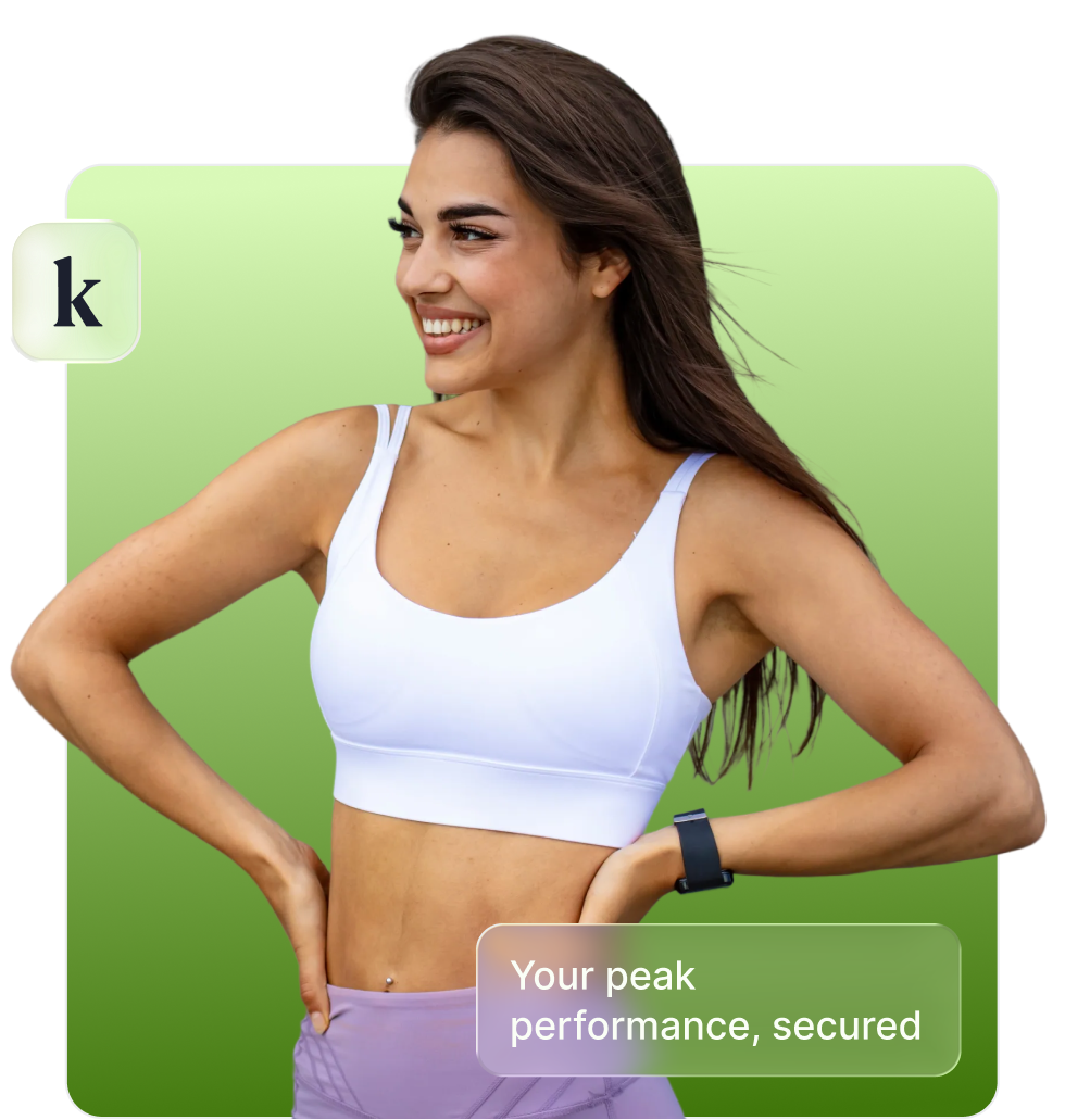 Smiling woman in white sports bra and purple leggings with hands on hips against a green gradient background.