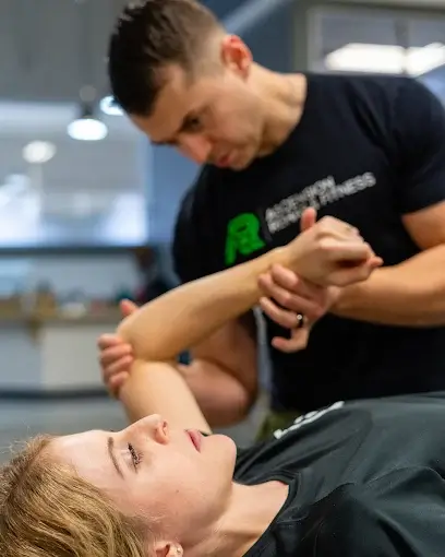 Physical therapist assisting a woman by gently stretching her arm during a therapy session. Ascension Rehab & Sports Therapy