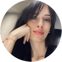 Primer plano de una mujer con cabello oscuro, apoyando la cabeza en la mano y mirando hacia la cámara.