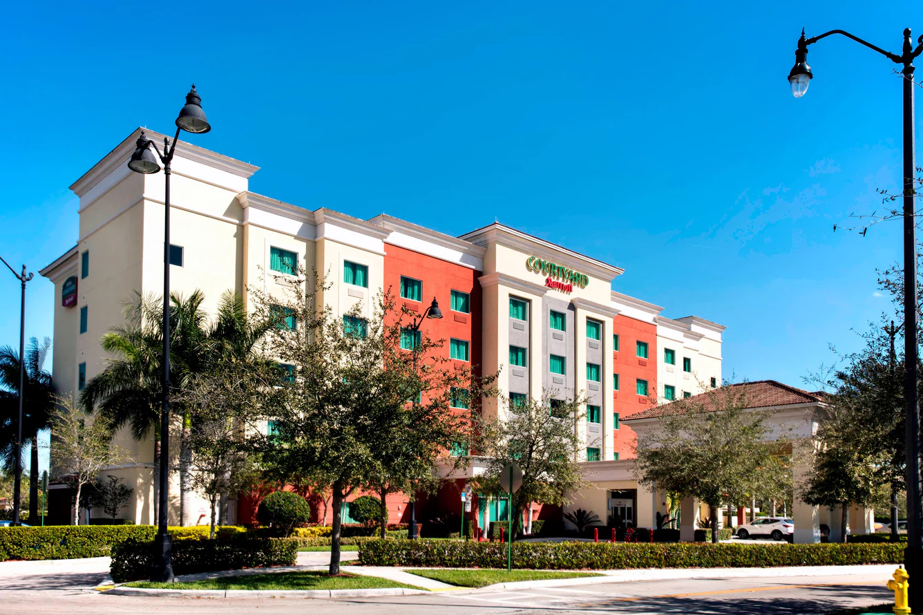 Courtyard hotel building with cream and orange facade under blue sky.