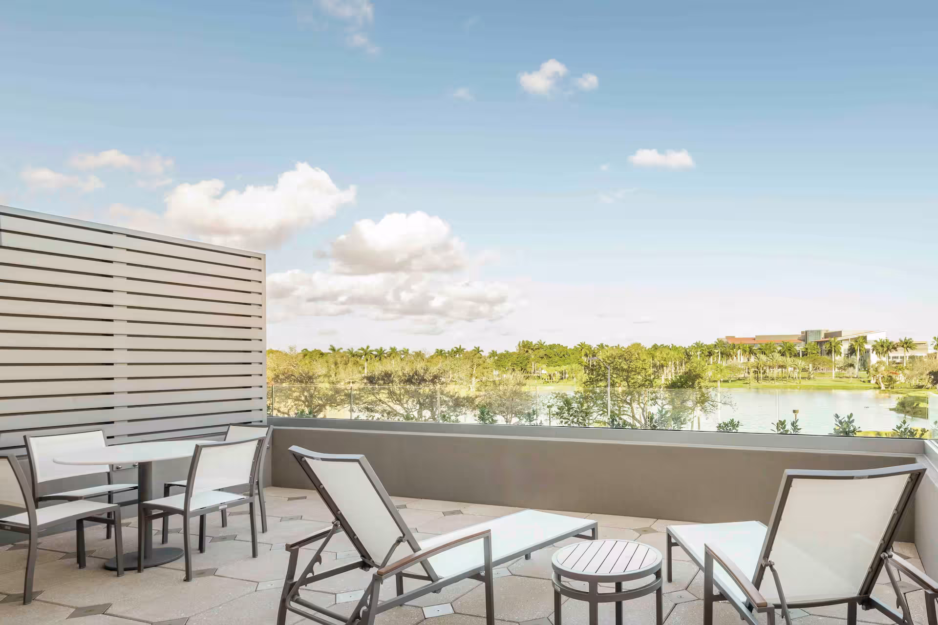Modern balcony with lounge chairs overlooking a lagoon and tropical landscape
