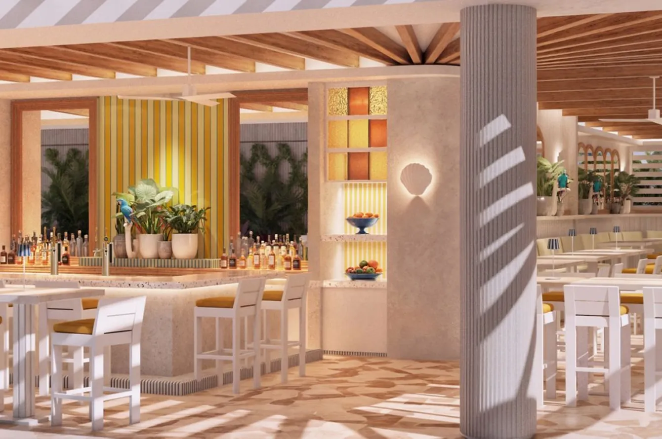 Bright tropical bar and dining area with white chairs, yellow cushions, plants, and wood ceiling beams.
