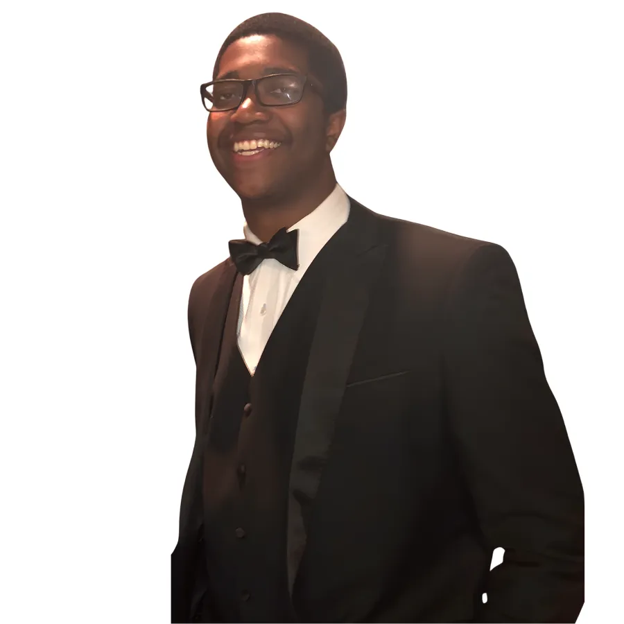 Man in tuxedo with bow tie and glasses smiling against white background