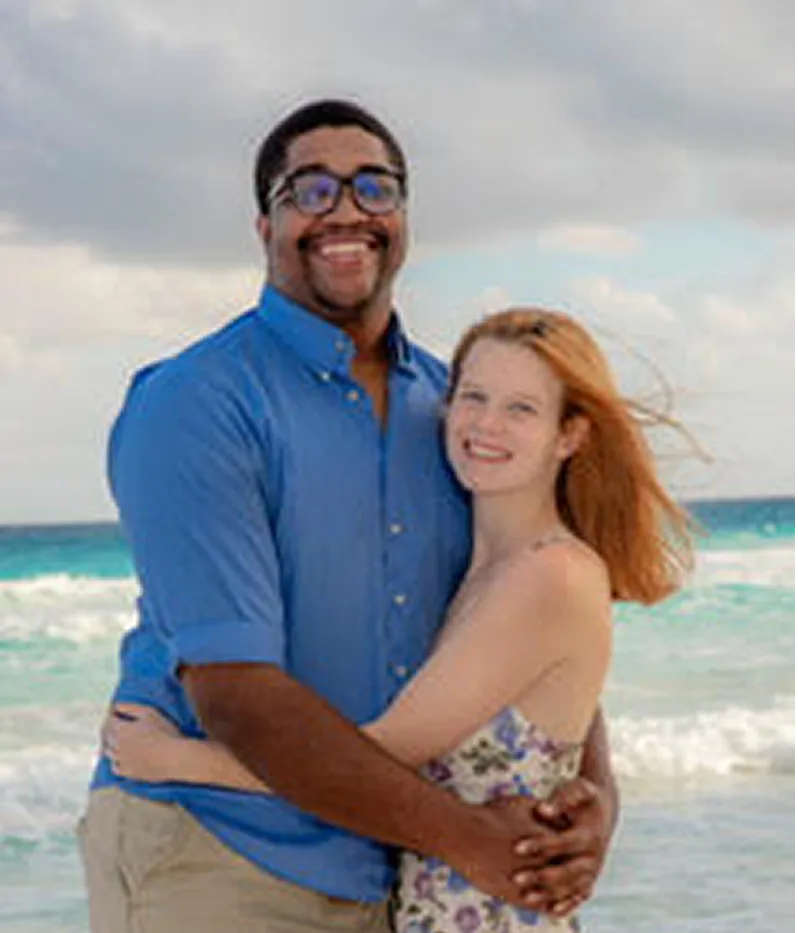 Happy couple embracing on a beach with ocean waves in background