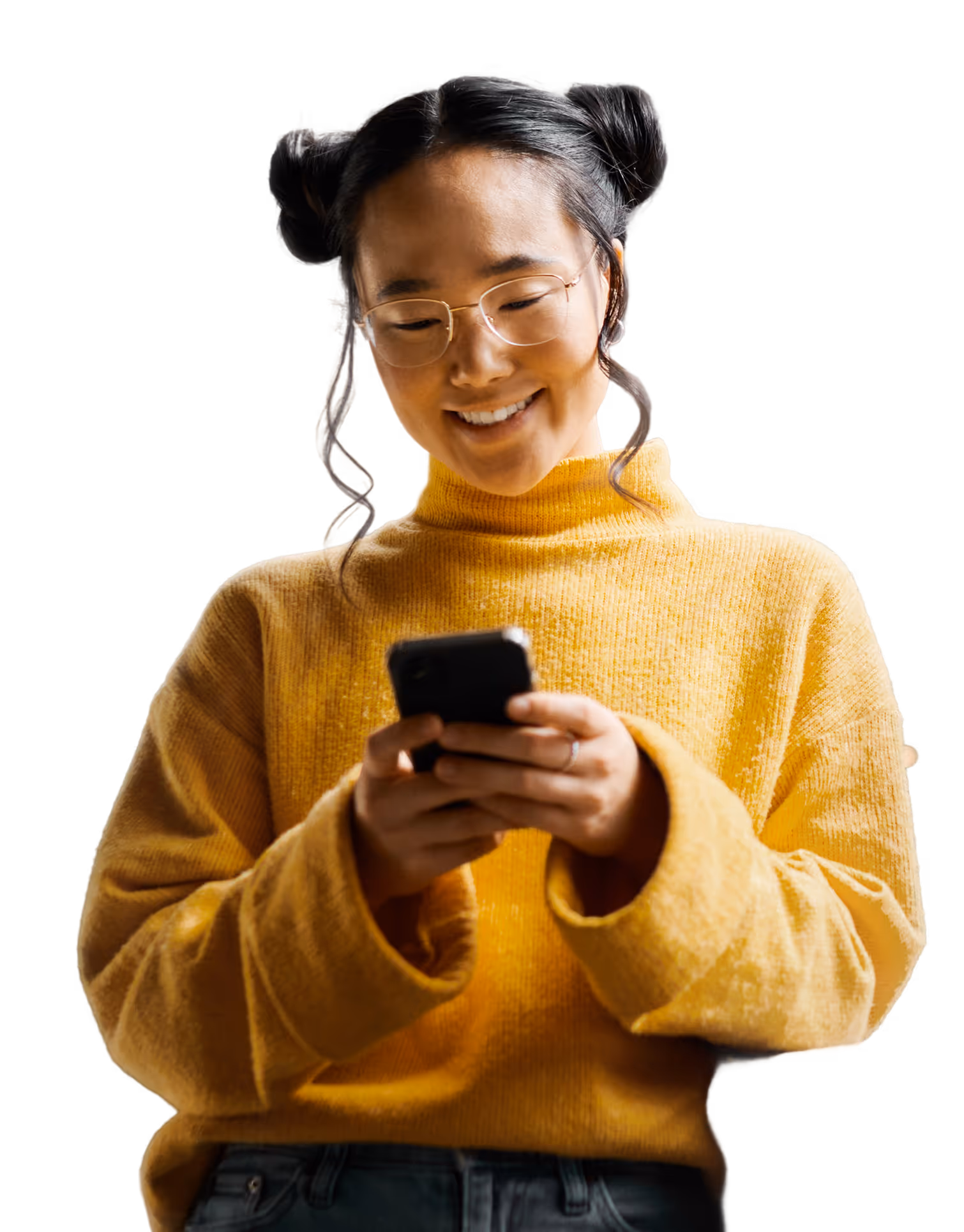 Smiling woman with glasses and hair buns looking at a phone, wearing a yellow sweater.