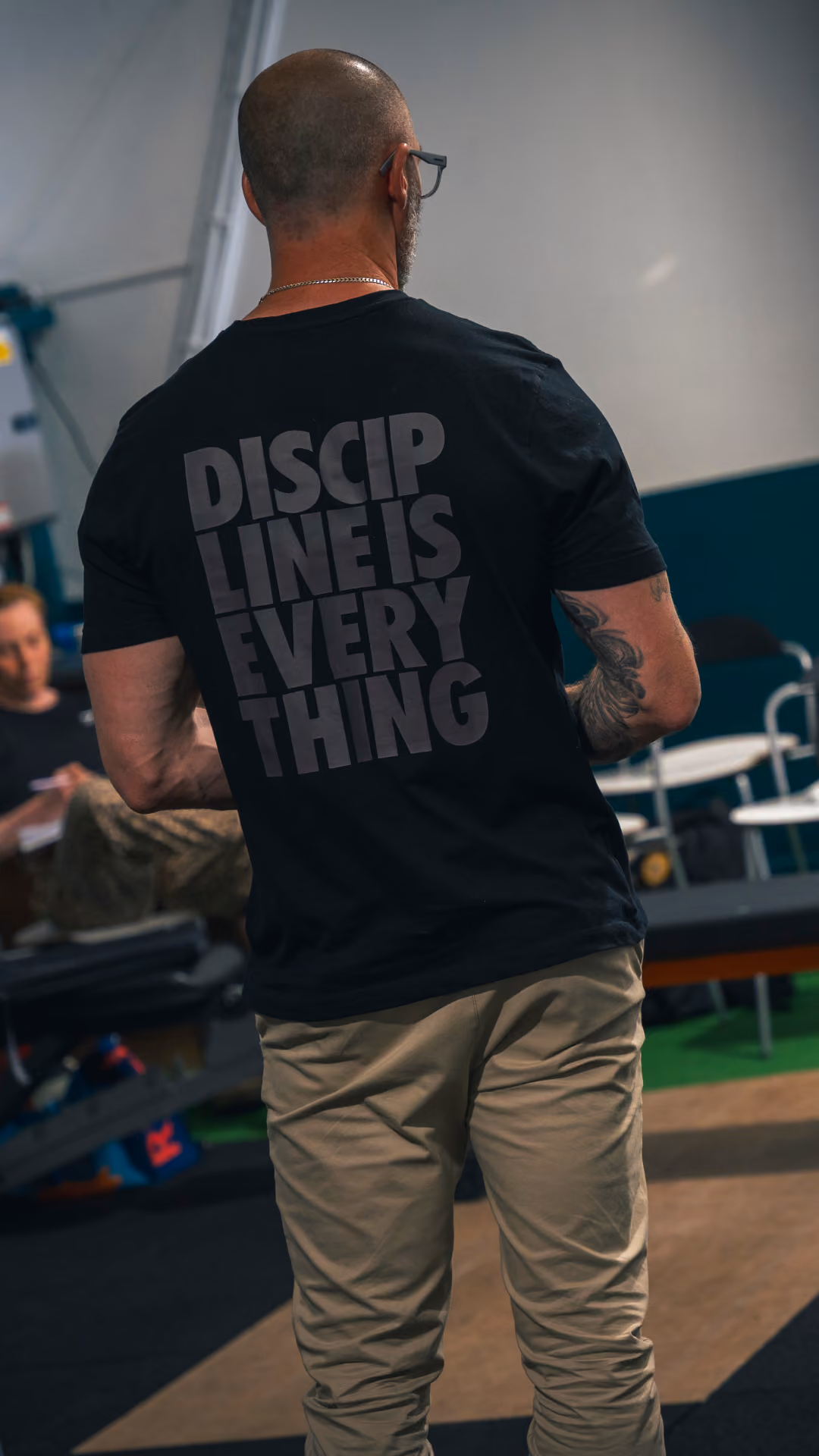 Man with a beard and tattoo wearing a black shirt that says Discipline is Everything.