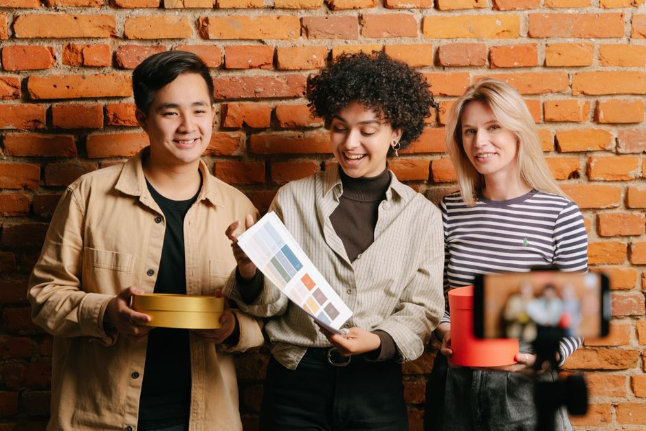 Three diverse people discussing packaging design with color samples, ideal for small business marketing.