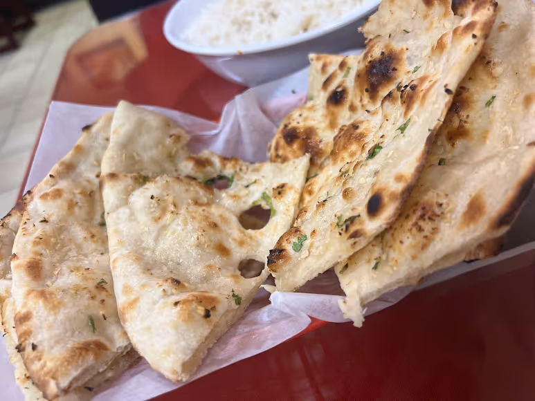 A pile of flat breads with green toppings.