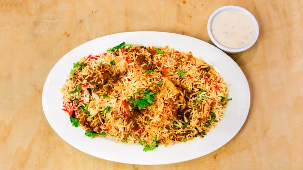 A white plate with rice and meat on it.