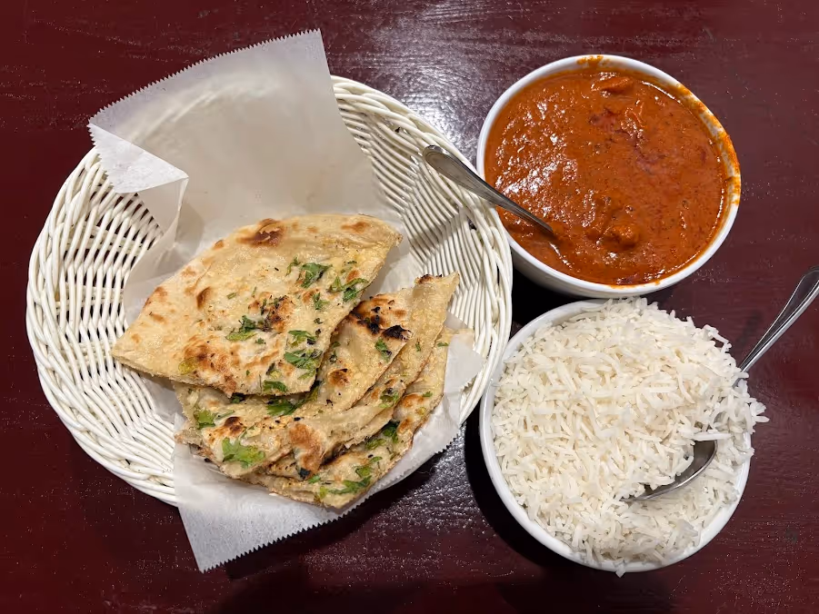 A basket of food with rice and a bowl of sauce.