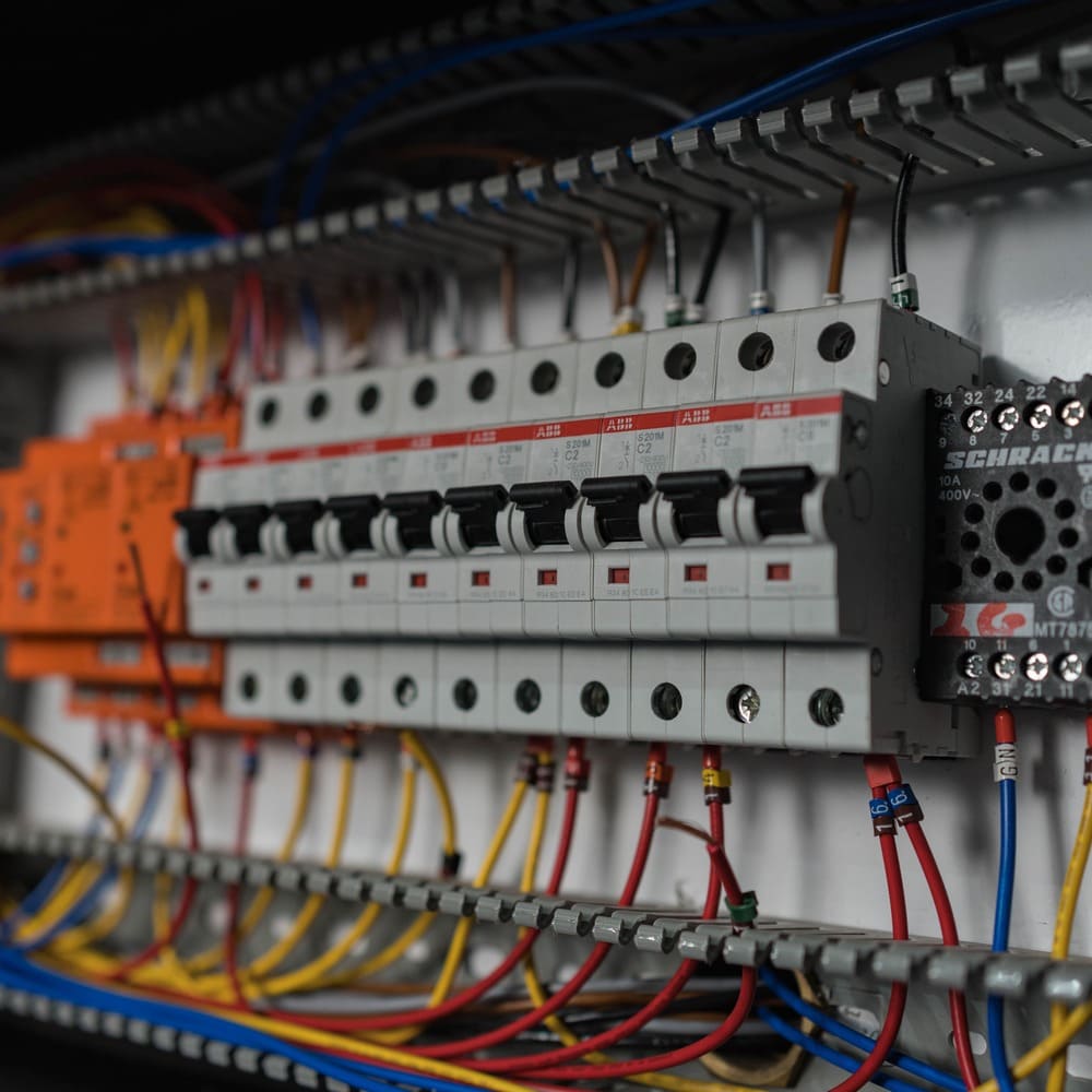 Close-up of an electrical circuit breaker panel with multiple switches and colorful wiring connections.