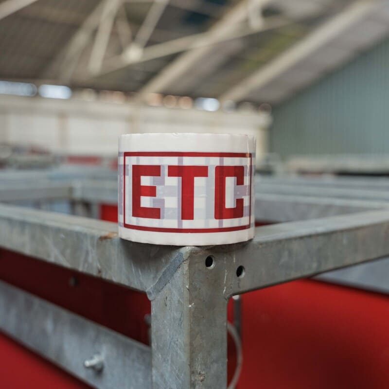 Metal structure corner with white tape labeled 'ETC' in red letters in an industrial setting.