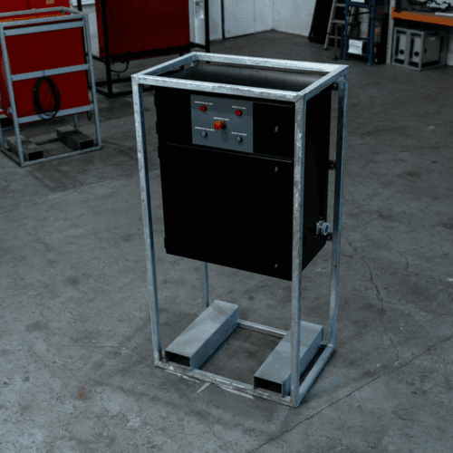 Industrial metal-framed electrical control panel with switches and buttons inside a workshop.