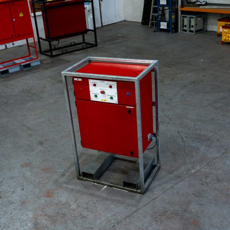 Red industrial machine enclosed in a metal frame standing on a concrete floor in a workshop.