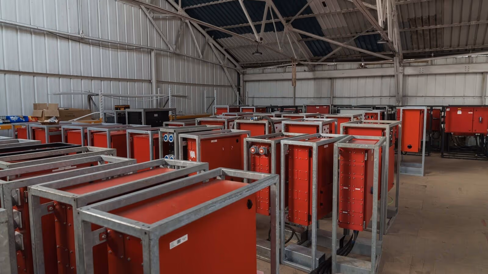 Warehouse interior filled with red industrial electrical panels in metal frames.