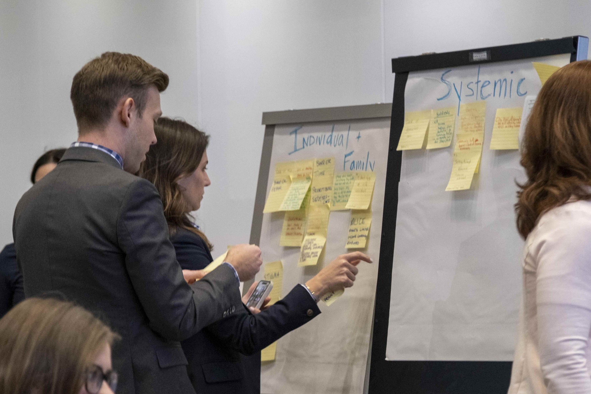 Two people discussing and placing sticky notes on flip charts at a Face the Fight Coalition Meeting.