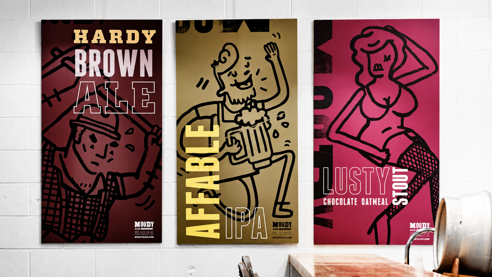 Large illustrated Moody Ales beer posters displayed inside the brewery featuring Hardy Brown Ale, Affable IPA and Lusty Stout branding.