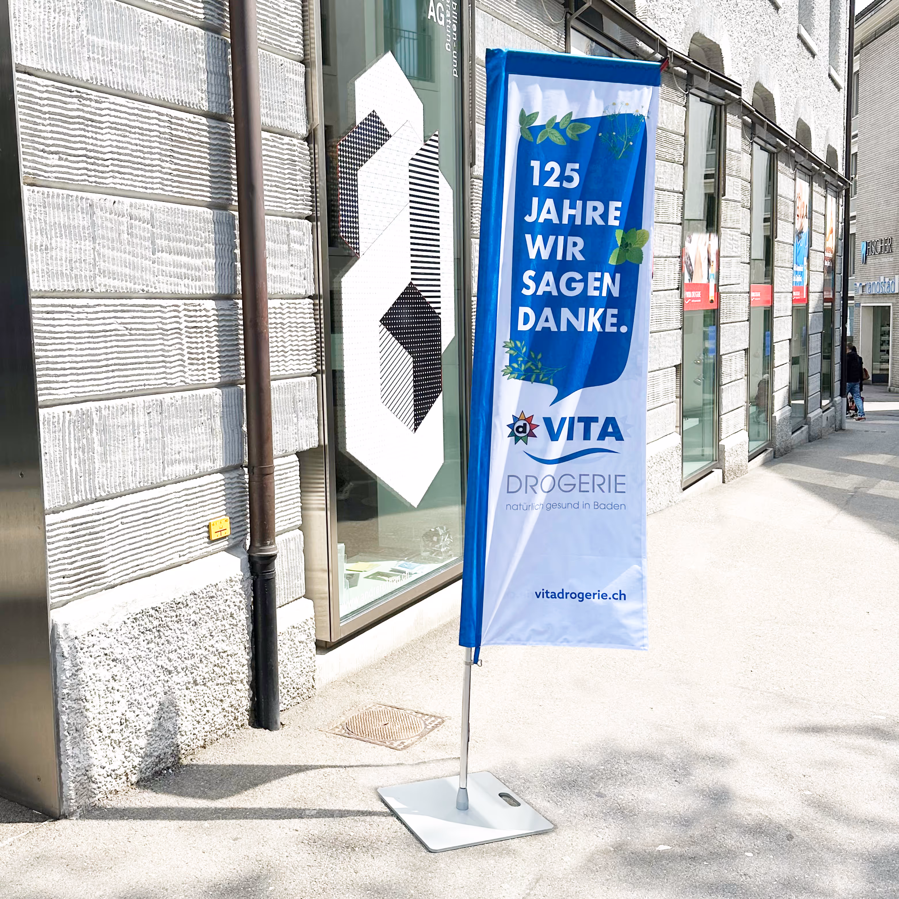 125 Jahre Vita Drogerie Baden: Jubiläumsbranding mit Mailing, Plakat, Busbeschriftung, Beachflags und Aufklebern. Wertschätzung mit System.