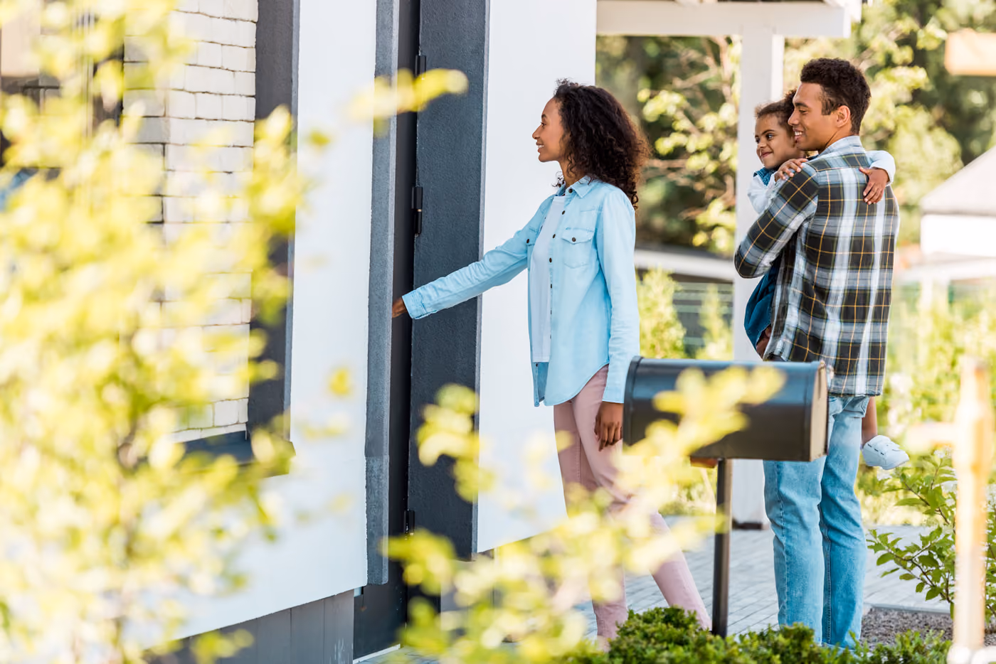 A family of 3 entering a home on a fall day