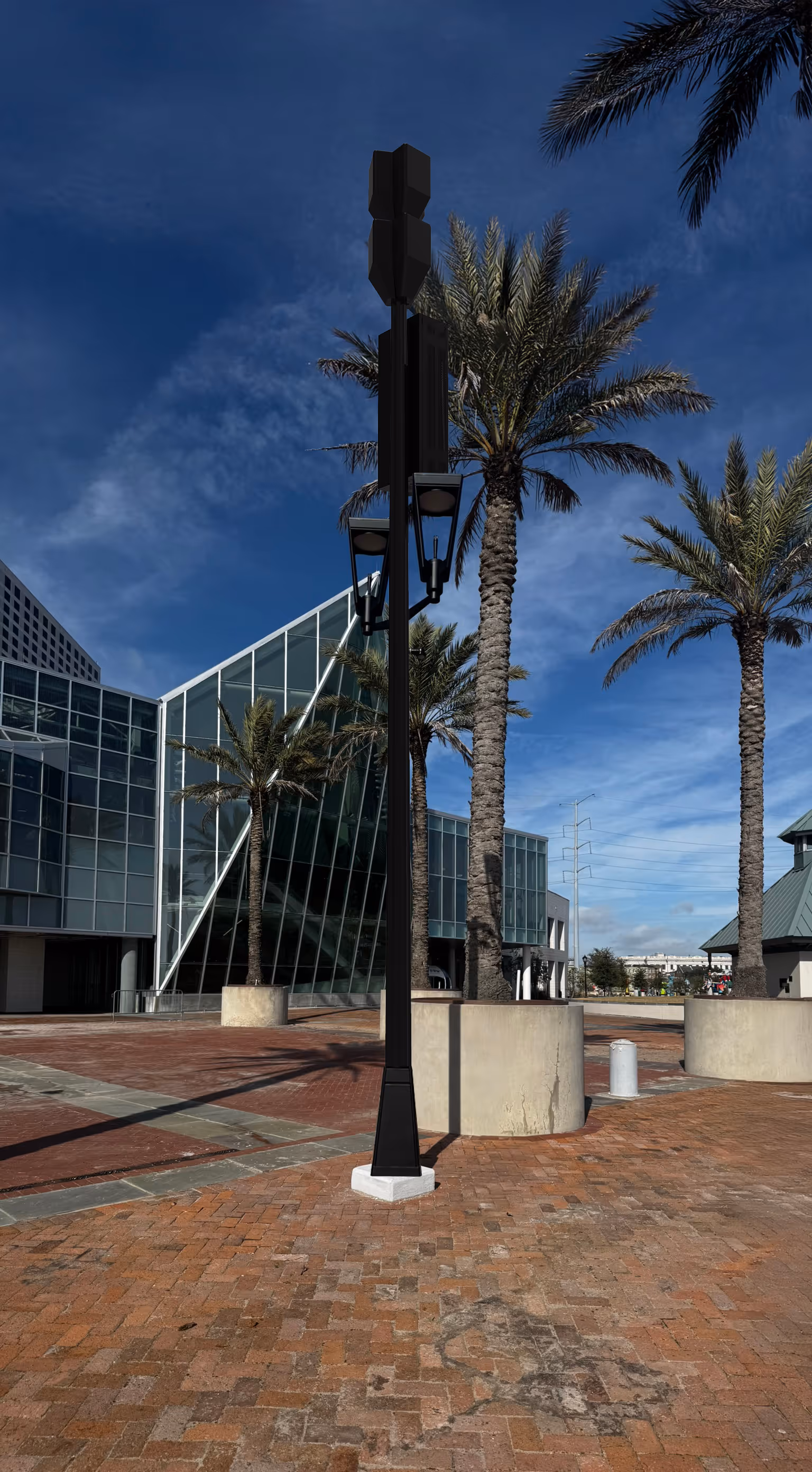 Black street lamp with two lanterns on a brick plaza surrounded by palm trees and modern glass buildings under a blue sky.