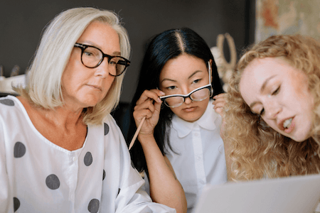 A woman is standing in front of a tree, smiling at the camera. Her right arm ends just below the shoulder, and her left arm ends just below the elbow.