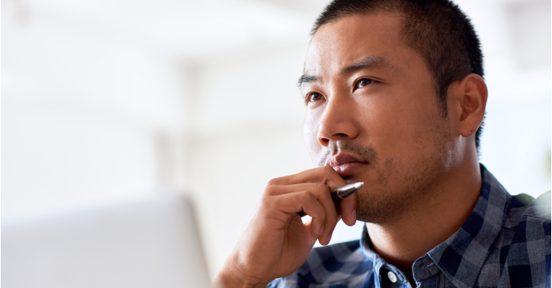 A closeup photo of a man with his chin resting on his hand. He appears to be thinking.