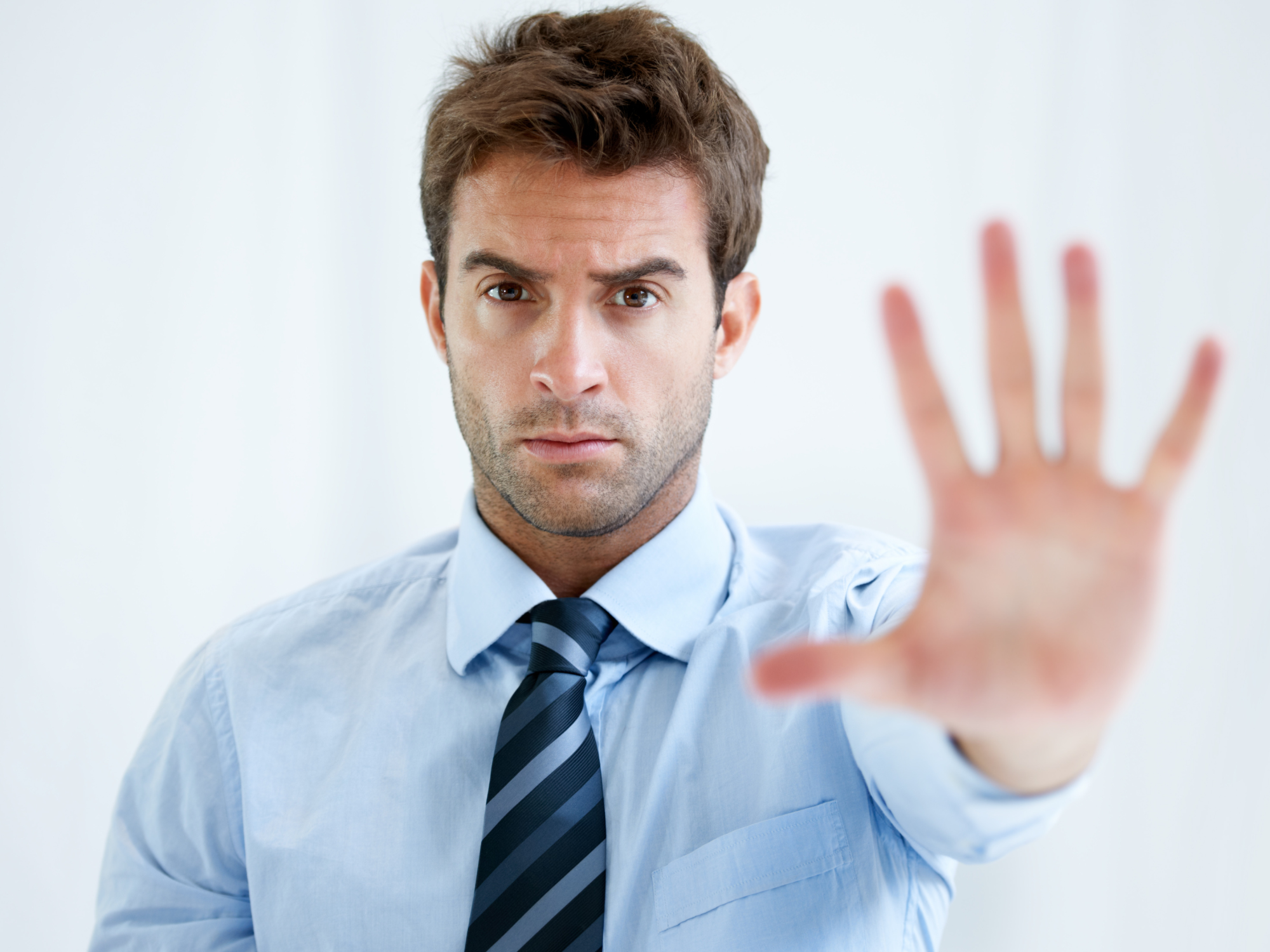 A photo of a man holding up his hand towards the camera in a "stop" gesture.