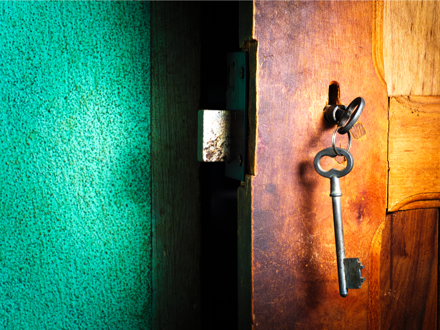 A photo of a door that has been left ajar. The key is still in the lock.