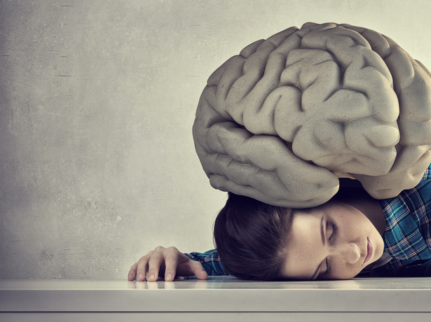 An image of a woman lying on the ground. There is a giant brain sitting on her head.