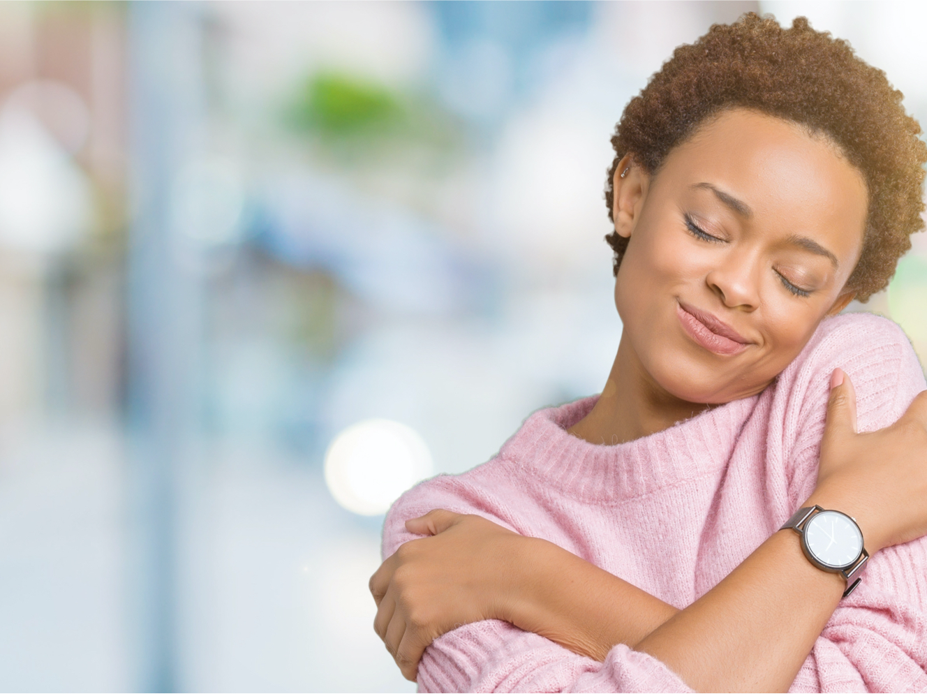 A photo of a woman with her own arms wrapped around herself in a self-hug.