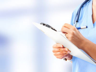 A closeup photo of a doctor writing something on a clipboard