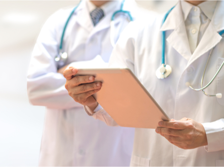 A closeup photo of two doctors reading off of a clipboard