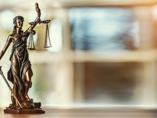 A photo of a mini Lady of Justice statue on a desk
