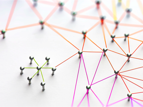 A photo of nails in a wall. They are connected with different color strings.